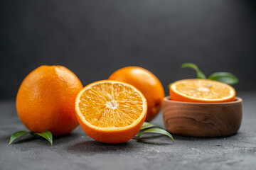 Horizontal view of set of whole and cut in half fresh oranges on dark background
