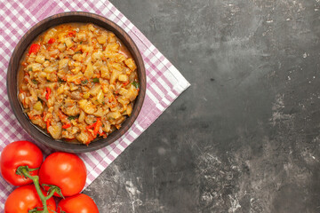 top view roasted eggplant salad in bowl tomatoes on pink white checkered tablecloth on dark background copy space