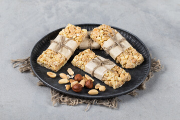 Fitness bars made of oatmeal, peanuts, hazelnuts on a plate on a light gray background