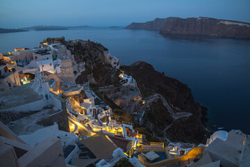 Oia town on Thira. Santorini island with colorful volcanic cliffs and deep blue sea aerial view