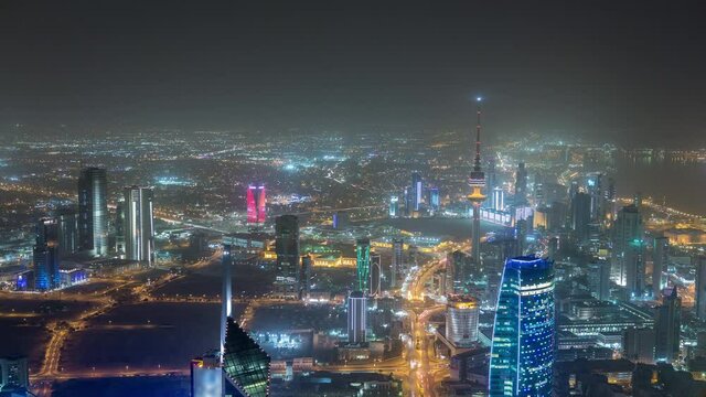 Skyline with Skyscrapers night timelapse in Kuwait City downtown illuminated at dusk. Aerial view from rooftop. Kuwait City, Middle East.
