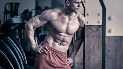 Fototapeta na wymiar Muscular minded bodybuilder resting after hard workout in gym