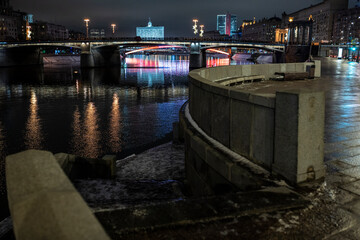 evening winter cityscape with river bridge and illuminated buildings