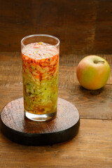 A glass of kiwi apples cocktail smoothies on a wooden table on a stand.