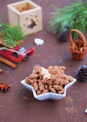 Homemade candied almonds in a white star bowl in a Christmas style on a brown concrete background. Christmas concept. Sweets recipes.