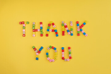 Thank you on bright yellow background. Words made of small colorful bricks with number....