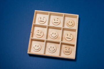 Tick Tack Toe with emoticons made of wooden circles. Positivity wins concept.
