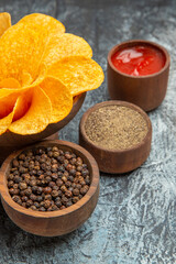 Half shot of homemade potato chips decorated like flower shaped and different spices ketchup on gray background