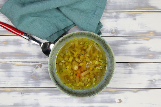 Top Down View On White Wood Table With Red Spoon, Fennel And Parsley Root, Blue Napkin And Bowl Homemade Winter Minestrone Root Vegetable Soup