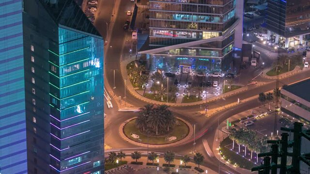 Skyline and traffic on crossroad with Skyscrapers night timelapse in Kuwait City downtown illuminated at dusk. Aerial view from rooftop. Kuwait City, Middle East.