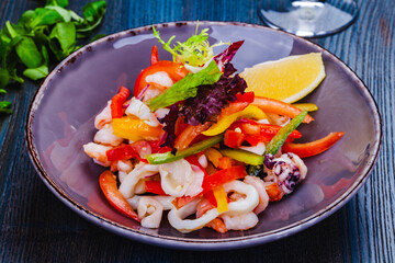 Salad with squid, bell pepper and onion on gray plate