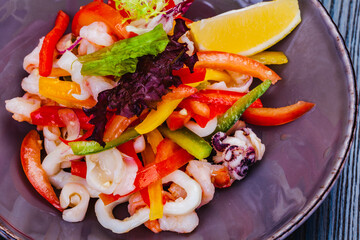 Salad with squid, bell pepper and onion on gray plate