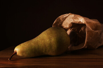 Una pera e un sacchetto di carta, primo piano su fondo scuro
