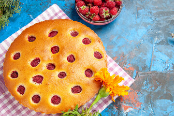 top view raspberry cake on kitchen towel bowl with raspberries on blue background free place