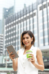 Fototapeta premium Successful beautiful asian business young woman using smart phone and coffee cup in hand , business concept