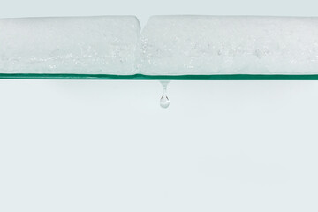 Melting ice on the glass shelf of the refrigerator with a drop of falling water