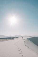 A man creating footprints walking the white gypsum sand dunes of White Sands National Park, New Mexico, USA. 