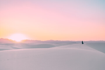 Silhouette of a girl walking the sand dues and watching the sunset in White Sands National Park, New Mexico, USA. 