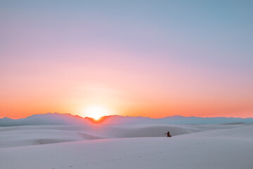 Silhouette of a female/girl/woman watching the colorful sunset over the sand dunes of White Sands National Park in New Mexico, USA.