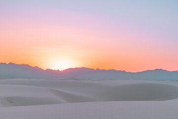 Fototapeta na wymiar A vibrant, colorful sunset over the white gypsum sand dune layers of White Sands National Park, New Mexico, USA.