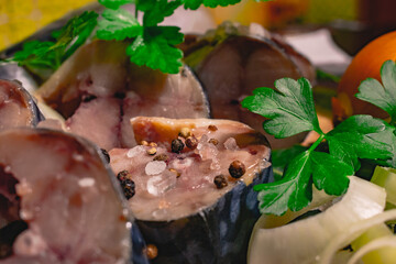Sliced ​​mackerel, prepared for pickling, with herbs, onions, spices and salt.