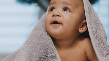 Close up of cute black baby with head covered with fluffy towel Christmass tree in the background....
