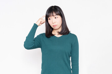 Fototapeta premium 白背景の前で考えるジェスチャーをする女性