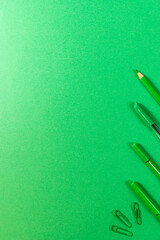 green pencils and pens on a green background in the corner
