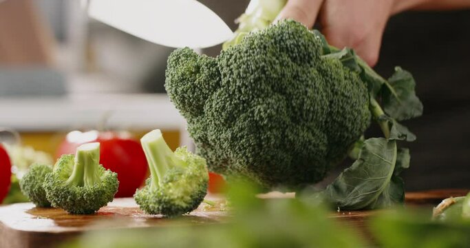 Chef using a knife cutting fresh raw broccoli cabbage. Cooker at home making a healthy vegetable meal, cutting up veggies - food and drink 4k footage