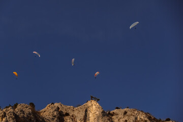 five paraglider on blue sky and rocky wall with a skywalk