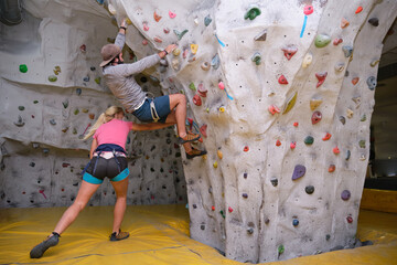 Two young friends climbing a wall on artificial rock climbing wall indoors. Extreme sports concept. © Ladanifer