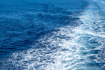 Boat white wake, on blue sea background, view from the ship. Mediterranean sea cruise