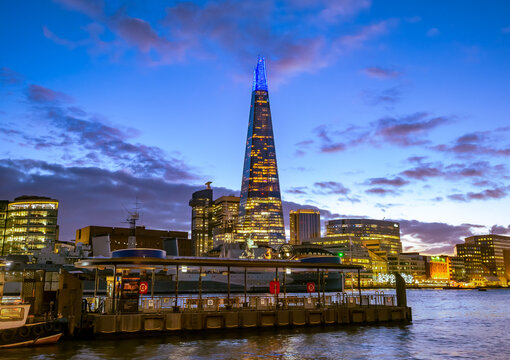 London, England, UK - December 5, 2020: The famous Shard and other buildings on the riverside of Thames river illuminated at dusk