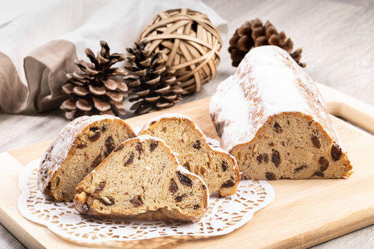 A traditional German Stolle (Christmas loaf) with nuts and raisins cut into slices on a black plate with a doillie