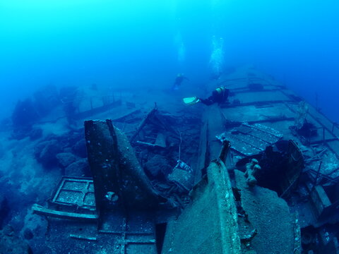 scuba divers exploring shipwreck scenery underwater ship wreck deep blue water ocean scenery of metal underwater © underocean
