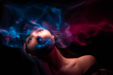 Girl, model photographed on a long exposure in the studio with color filters. Portrait