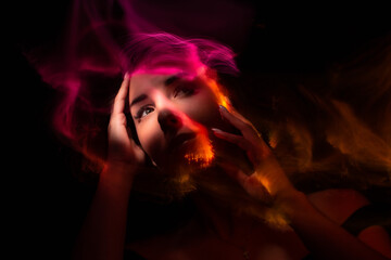 Girl, model photographed on a long exposure in the studio with color filters. Portrait