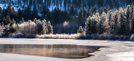 Image of a snow covered lake. Ice and snow have fallen and there is a haze of fog above the lake.