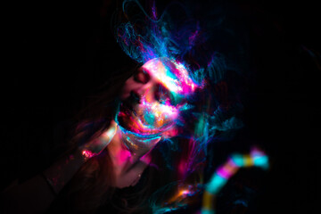 Portrait of a beautiful woman in colored beams of a projector. Streaks of light and shadow on the skin.