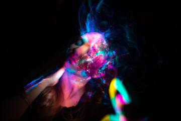 Portrait of a beautiful woman in colored beams of a projector. Streaks of light and shadow on the skin.