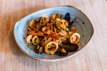 delicious pasta dish with cheese on top served in clay plate on wooden table