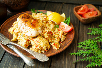 Cous Cous, chicken and vegetables on dark wooden table