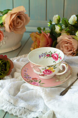 Porcelain vintage tea cup over wooden table with roses