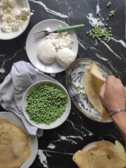 Italia homemade vegetarian lasagna with fresh mozzarella cheese, green peas, hot chili in a black marble kitchen table.