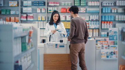 Pharmacy Drugstore Checkout Cashier Counter: Beautiful Female Pharmacist Scans Barcode and Handsome Young Man Talks to a Cashier and Pays for the Health Care Products at the Checkout Counter.