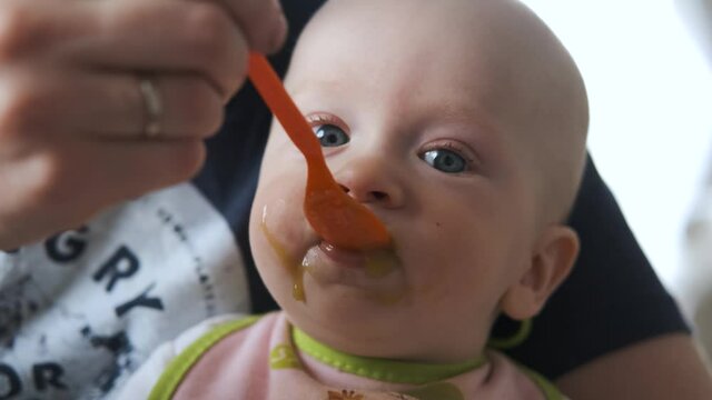 close-up of a baby being spoon-fed puree