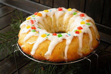 Candied berries bundt cake with lemon sugar glaze on wooden table. Homemade autumn and winter cozy holiday dessert on rustic table