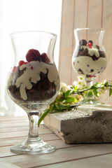 Yogurt with chocolate cream, chopped chocolate and muesli served in glass on wooden table