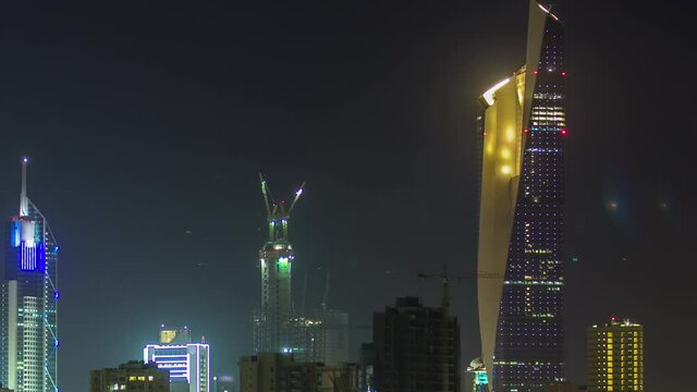 Skyline with Skyscrapers night timelapse in Kuwait City downtown illuminated at dusk. View from beach with reflection in water. Kuwait City, Middle East.