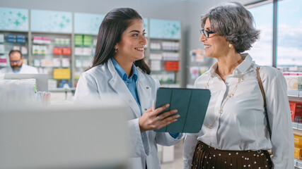 Pharmacy Drugstore: Senior Woman Chooses to Buy Medicins. Professional, Helpful Pharmacist Uses Digital Tablet Computer and Advicing Customer Best Option. Modern Pharma Store Health Care Products